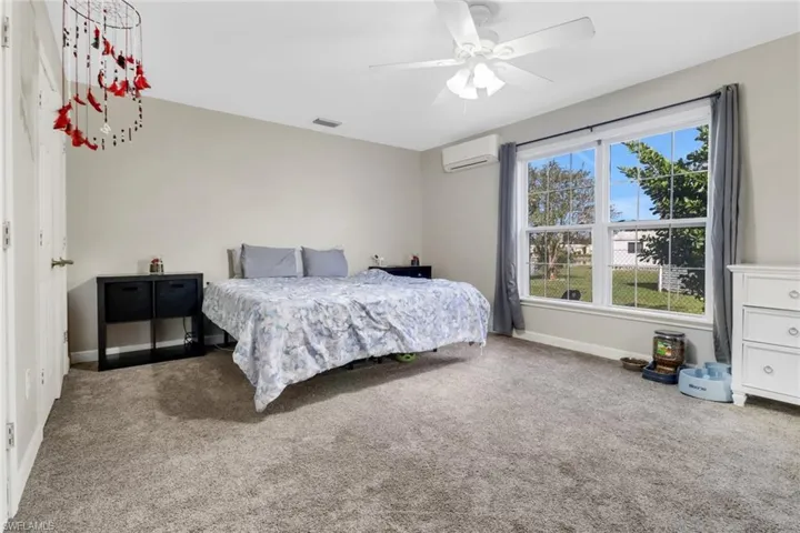 Bedroom featuring carpet, a wall unit AC, and ceiling fan