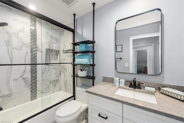 Guest Bathroom featuring shower / bath combination with glass door and vanity