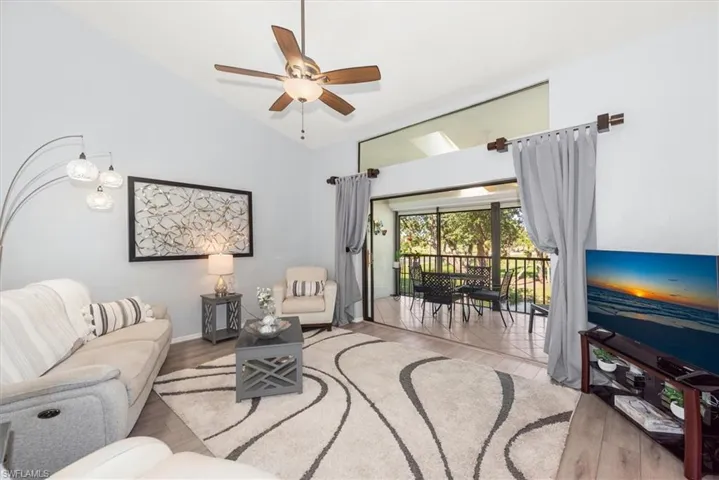 Living area featuring vaulted ceiling, light wood-style floors, and a ceiling fan