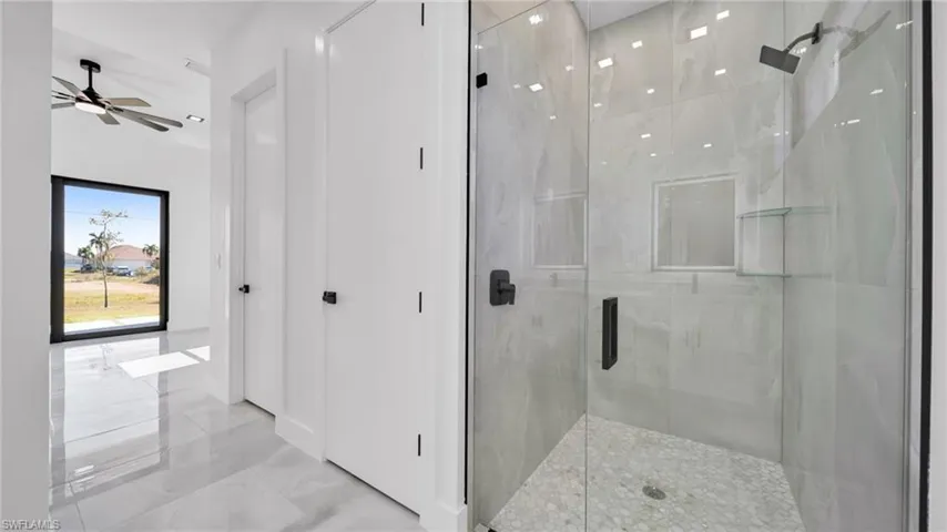 Bathroom with a marble finish shower and light marble finish flooring