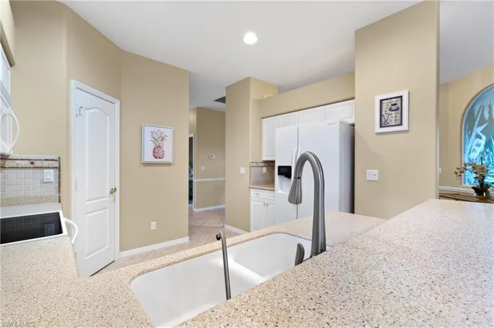Kitchen featuring sink, white appliances, white cabinetry, decorative backsplash, and kitchen peninsula