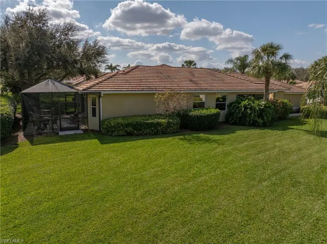 Back of property featuring a yard and glass enclosure