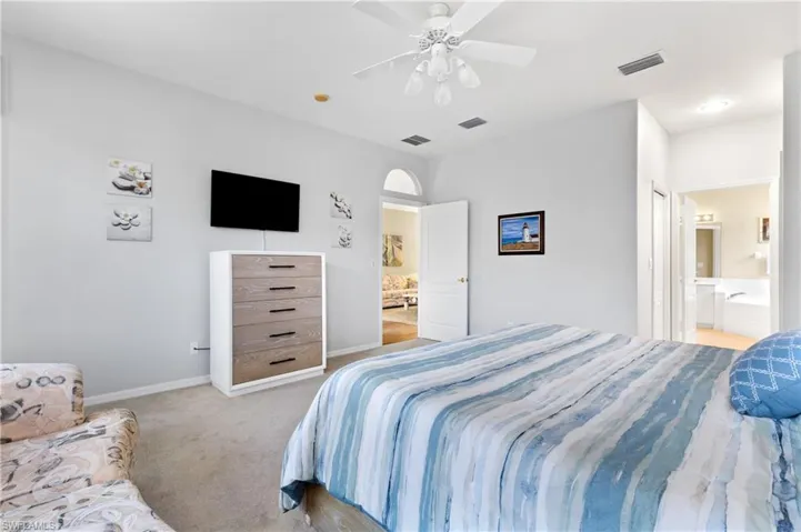 Carpeted bedroom with ensuite bath and ceiling fan
