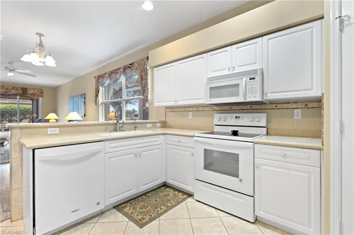 Kitchen with sink, tasteful backsplash, pendant lighting, white appliances, and white cabinets