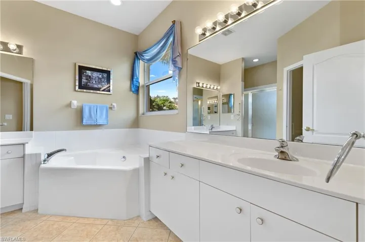 Bathroom featuring tile patterned flooring, vanity, and separate shower and tub