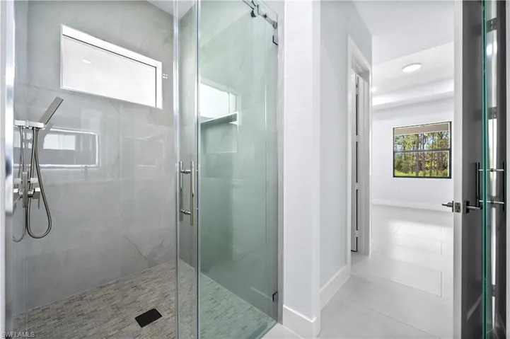 Full bath with a marble finish shower and baseboards