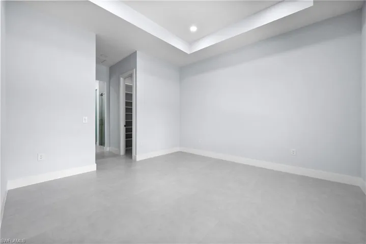 Unfurnished room with finished concrete flooring, recessed lighting, and a raised ceiling