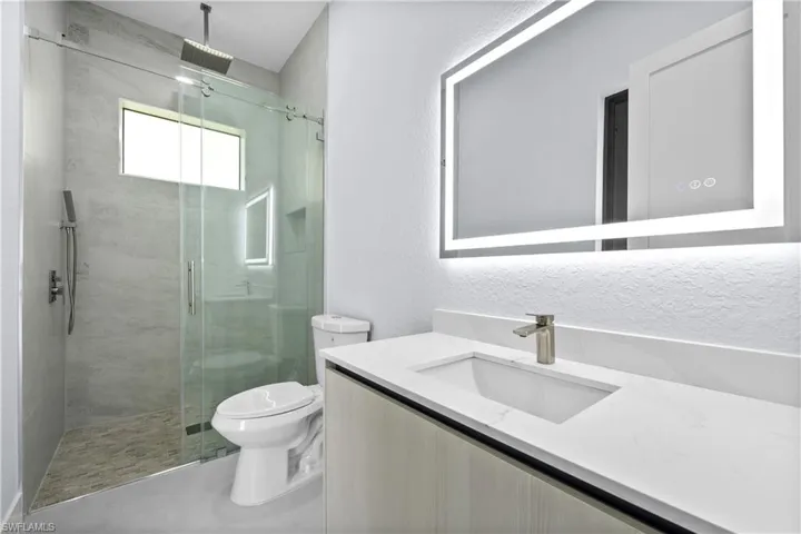 Bathroom featuring vanity, a textured wall, and a shower stall