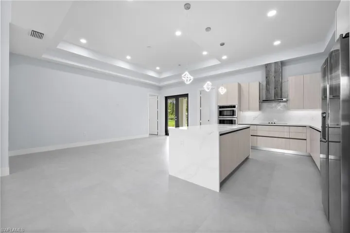 Kitchen with modern cabinets, a kitchen island, light wood finish cabinets, tasteful backsplash, and light stone counters