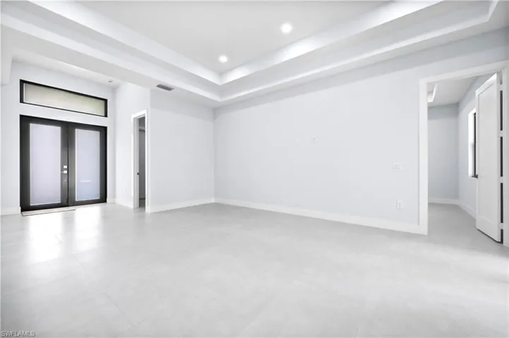 Spare room featuring french doors, a tray ceiling, and recessed lighting