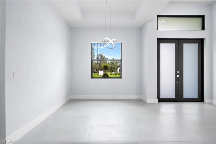 Foyer entrance with french doors, a raised ceiling, and suspended lighting