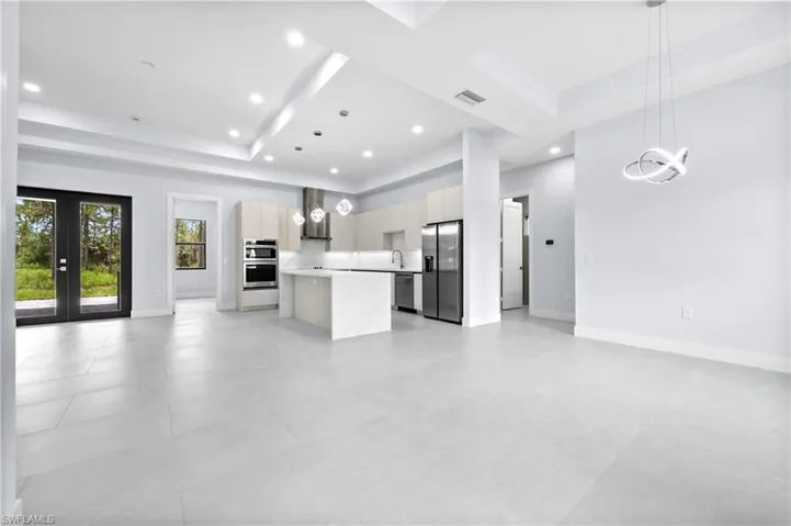 Kitchen featuring open floor plan, hanging lights, stainless steel appliances, a kitchen island, and a raised ceiling