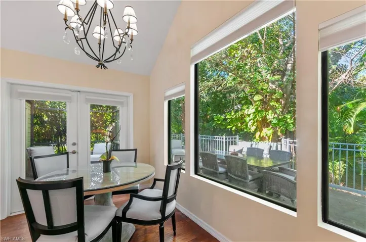 Dining area with dark wood-style flooring, a chandelier, french doors, and lofted ceiling