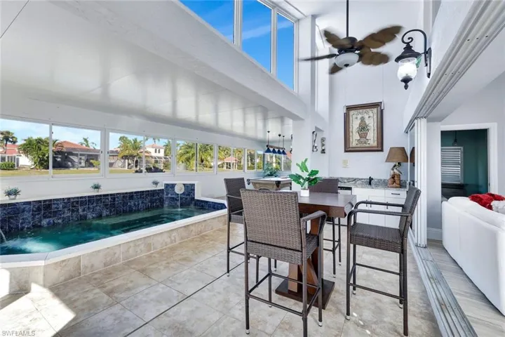 Enclosed lanai with tile flooring, large windows, and an indoor spa overlooking the lake.