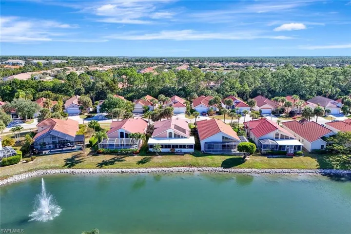 Wide aerial shot of the lake with fountain feature and waterfront homes lining the shoreline.