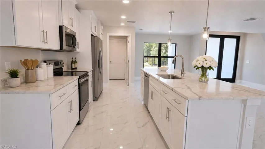 Contemporary kitchen featuring white cabinetry, stainless steel appliances, light-toned countertops, and large format tile flooring