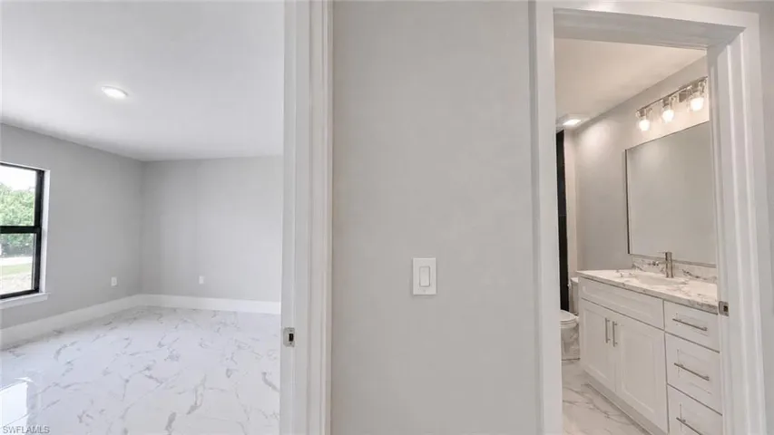 Modern bathroom vanity featuring a white cabinet, stone countertop, and chrome faucet