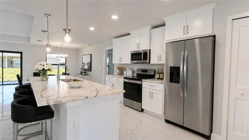 Modern kitchen featuring a large central island with a built-in sink and pendant lighting
