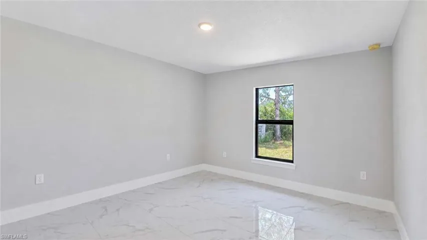 Spacious room featuring large format tile flooring, a window with exterior views, recessed lighting, and a neutral color palette