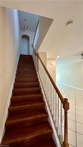 Stairway with arched walkways, recessed lighting, tile patterned flooring, and ceiling fan