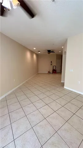 Empty room featuring a ceiling fan, recessed lighting, arched walkways, light tile patterned floors, and a textured ceiling