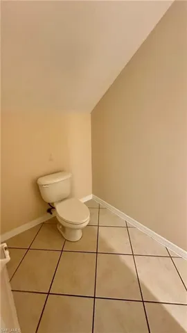 Half bath featuring lofted ceiling and light tile patterned floors