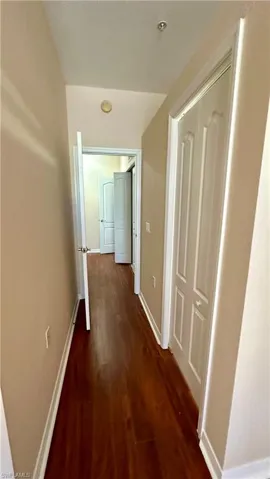 Hall with dark wood-style flooring and baseboards