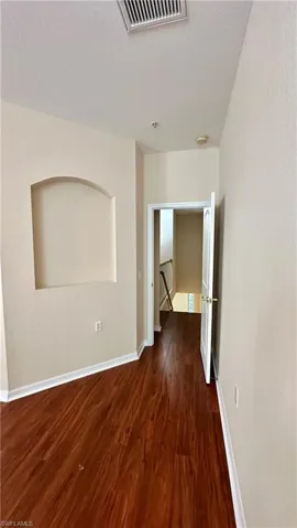 Spare room with dark wood-style floors and baseboards