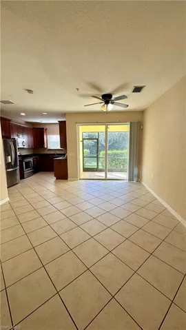 Unfurnished living room featuring a textured ceiling, healthy amount of natural light, ceiling fan, and light tile patterned floors