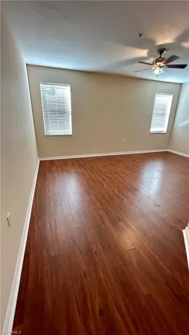 Spare room with dark wood-style floors and a ceiling fan
