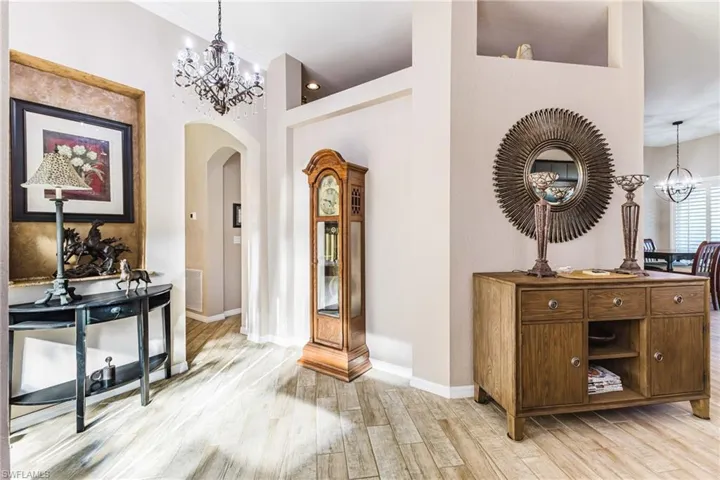 Foyer featuring hanging lights, arched walkways, light wood-style flooring, and a high ceiling
