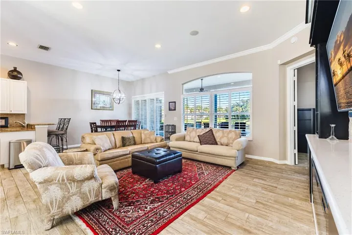 Living room with light wood-type flooring, hanging lights, and ornamental molding