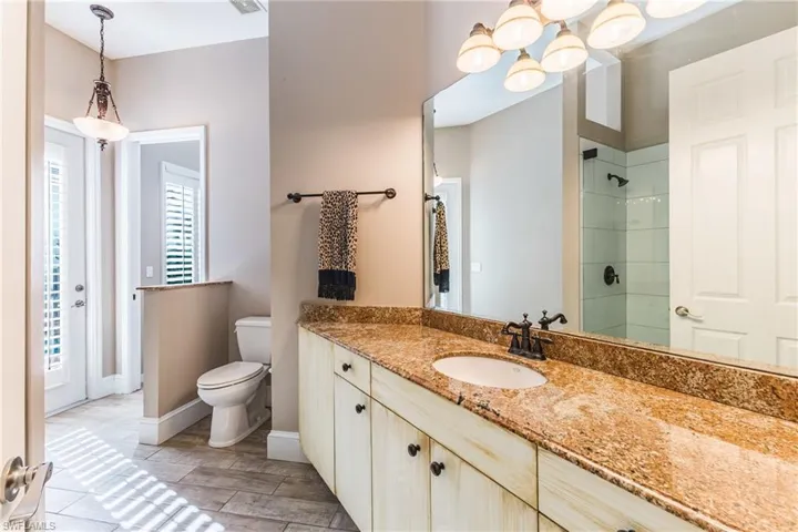 Full bath featuring vanity, tiled shower, and suspended lighting