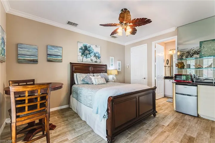 Bedroom featuring ornamental molding, light wood-style floors, freestanding refrigerator, microwave, sink and ceiling fan
