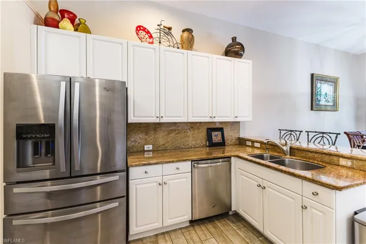 Kitchen featuring stainless steel appliances, dark stone counters, white cabinetry, and a peninsula