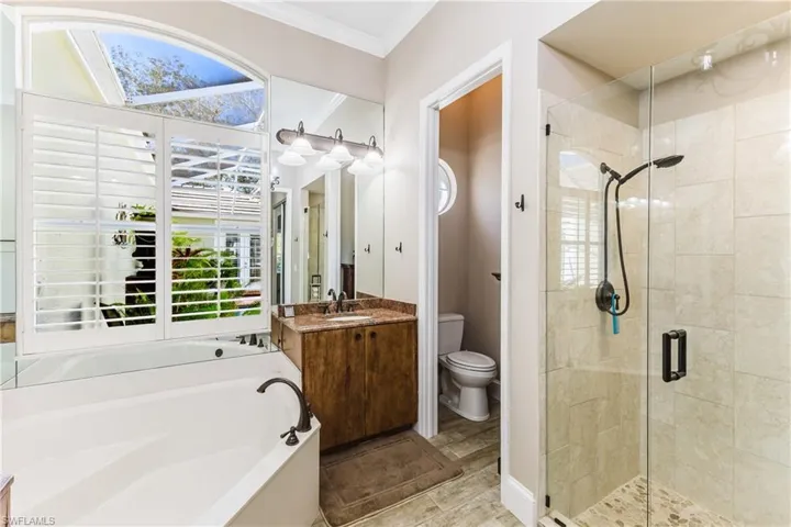 Full bathroom with vanity, a garden tub, a shower stall, ornamental molding, and light wood-style floors