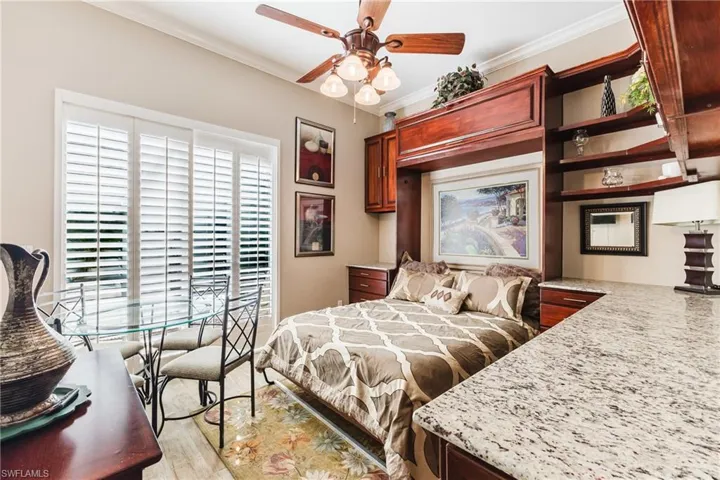 Bedroom with Murphy bed, crown molding, a ceiling fan, and light wood-style floors