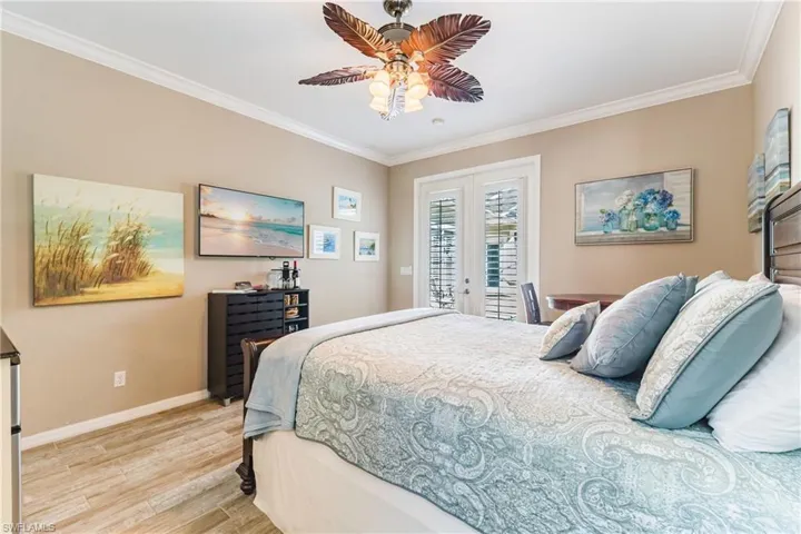 Bedroom featuring light wood finished floors, separate access to outside, crown molding, french doors, and a ceiling fan