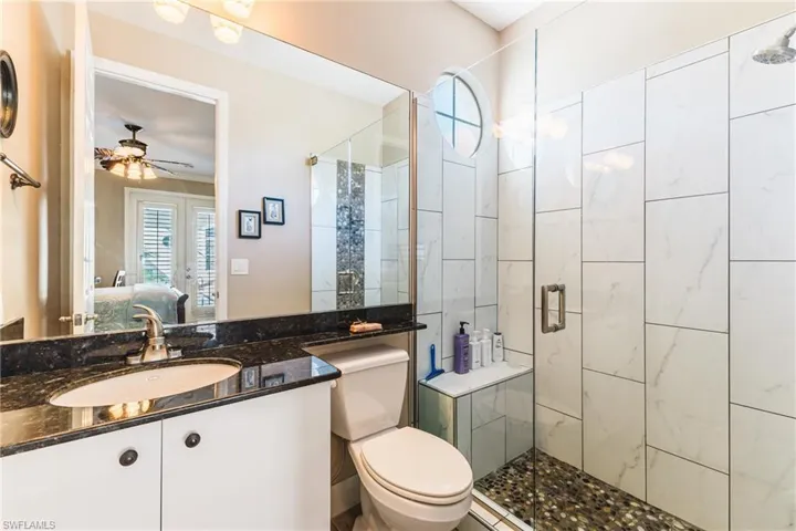 Bathroom featuring healthy amount of natural light, connected bathroom, a stall shower, and vanity