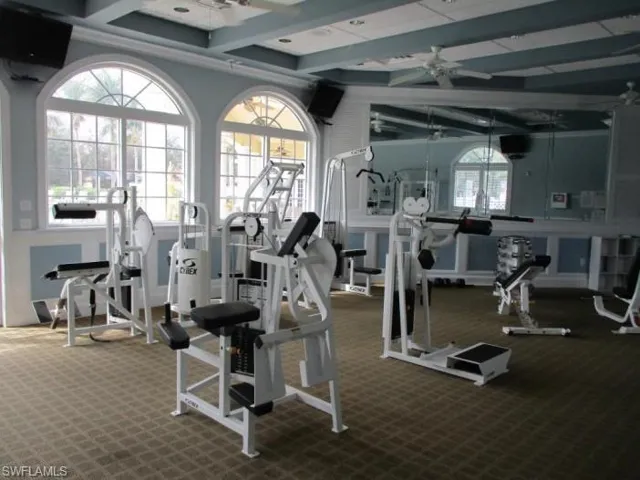 Exercise room with beamed ceiling, a ceiling fan, and carpet floors