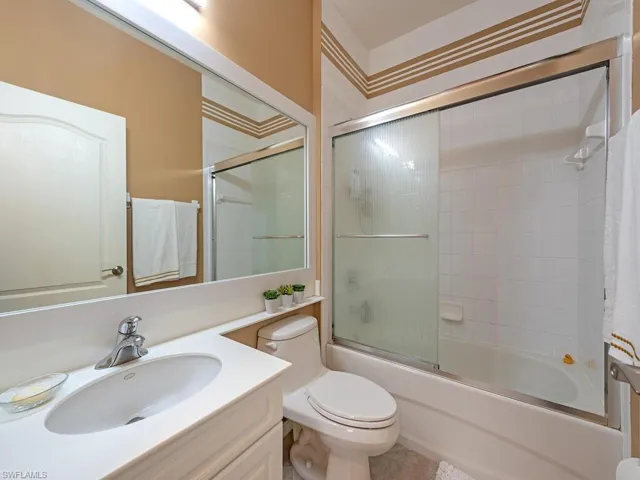 Bathroom with shower / bath combination with glass door and vanity.