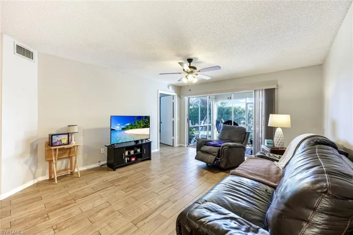 Living area featuring a textured ceiling, light wood-style floors, and a ceiling fan