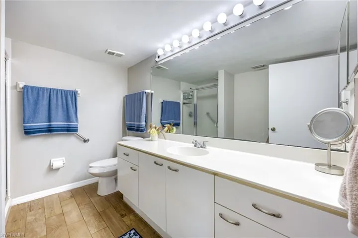 Full bathroom with vanity, a stall shower, and light wood-style flooring