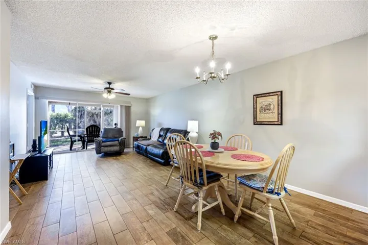 Dining space featuring a ceiling fan, a textured ceiling, light wood-type flooring, and suspended lighting
