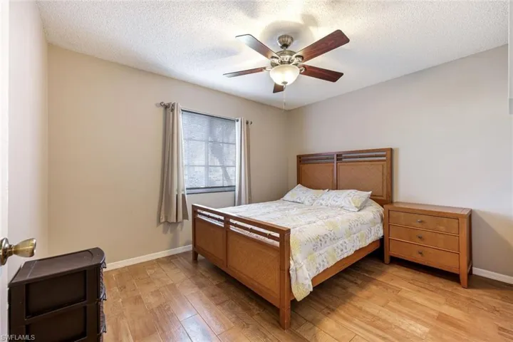 Bedroom with light wood-style floors, ceiling fan, and a textured ceiling
