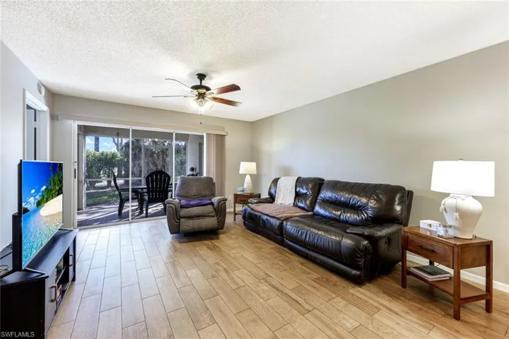 Living room with ceiling fan, light wood finished floors, and a textured ceiling