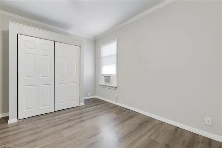 Unfurnished bedroom with a closet, crown molding, and light hardwood / wood-style flooring