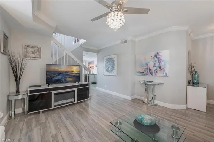 Living room with light hardwood / wood-style flooring, ornamental molding, and ceiling fan