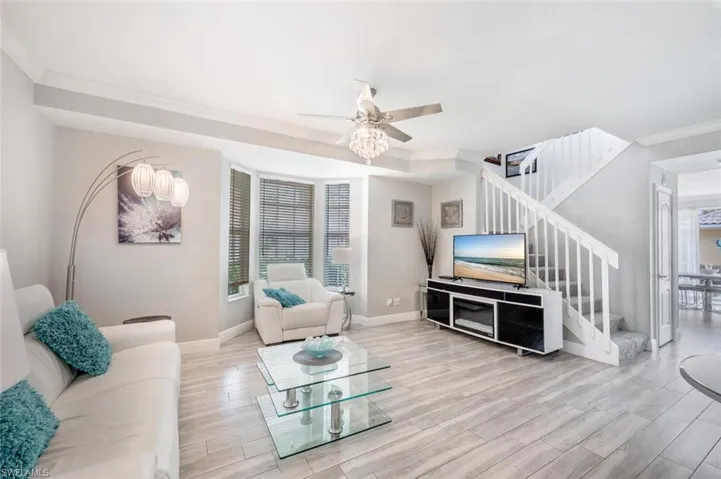 Living room with light wood-type flooring, ceiling fan, and ornamental molding