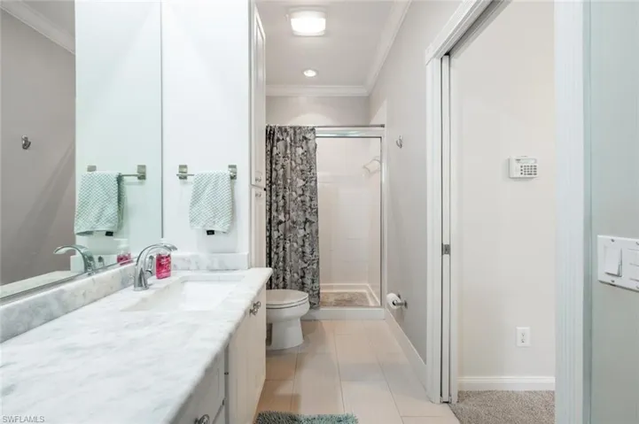 Bathroom featuring toilet, vanity, tile patterned floors, a shower with curtain, and ornamental molding